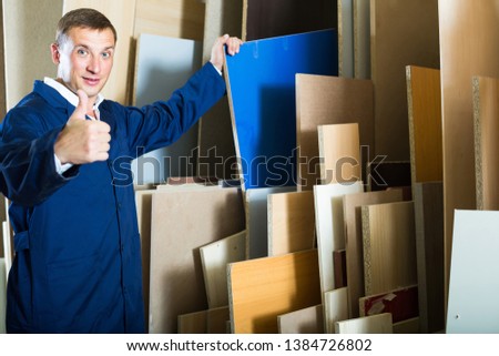 portrait of happy american  man in uniform choosing compressed densified wood in picture framing atelier