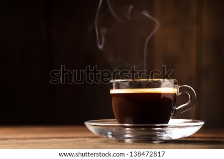 Cup of coffee with  fume on the wooden background