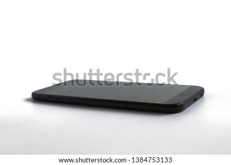 Smartphone with a dark display located on flat white surface. Mobile isolated on white background