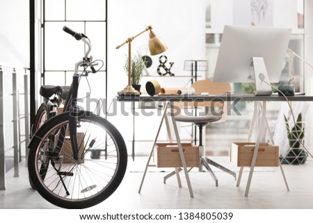 Stylish office interior with comfortable workplace and bicycle