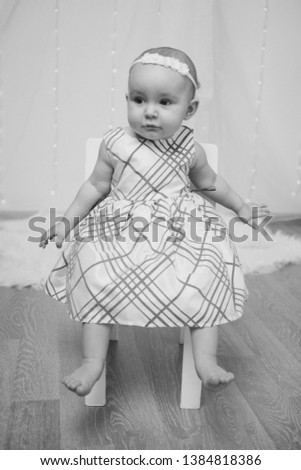 a little girl in a dress sits on a chair and smiles