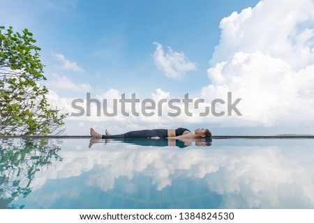 Vacation of Beautiful Attractive Asian woman relaxing in yoga Savasana pose on the pool above the beach with beautiful sea in Tropical island,Feeling comfortable and relax in holiday,Vacations Concept Royalty-Free Stock Photo #1384824530