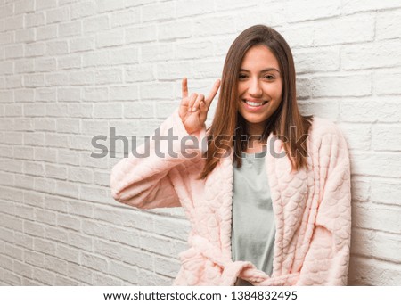 Young woman wearing pajama doing a rock gesture