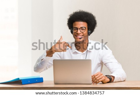 Young telemarketer black man person pointing by hand to a shirt copy space, proud and confident