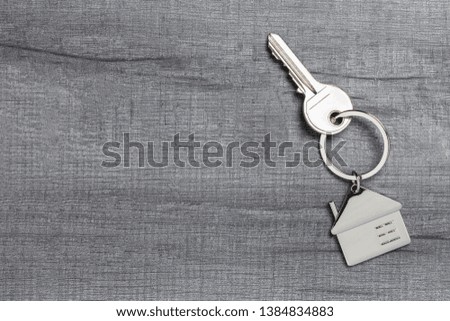 House keychain and key on wooden table with copy space