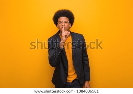 Young business african american man over an orange wall keeping a secret or asking for silence