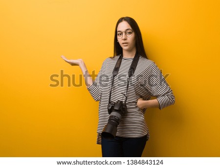 Young photographer woman holding something with hand