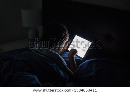 Child playing on a tablet in bed Royalty-Free Stock Photo #1384853411