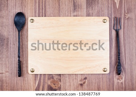 Wooden board blank with vintage spoon and fork on wood background