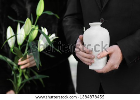 Couple with mortuary urn and flowers at funeral Royalty-Free Stock Photo #1384878455