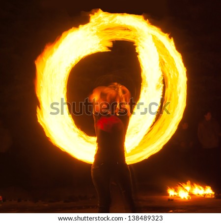 Girl with poi performs fire circle. Fireshow