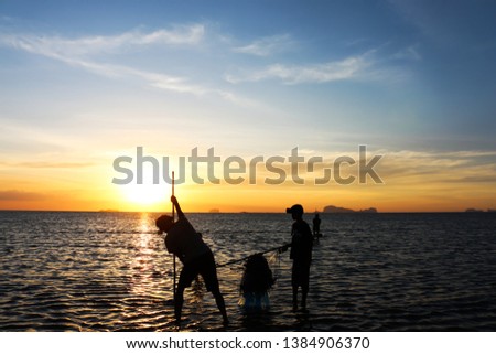 silhouette of fisherman family play in the sea at the sunset.