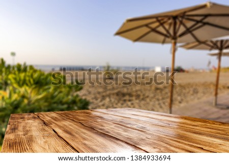 Wooden table background of free space for your decoration and summer landscape of beach. Sunny morning time and blue sky. 