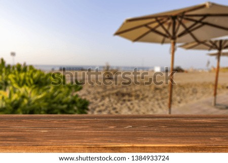 Wooden table background of free space for your decoration and summer landscape of beach. Sunny morning time and blue sky. 