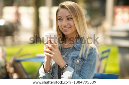  Happy young woman or teenage girl with cup drinking coffee at city street cafe terrace and dreaming .