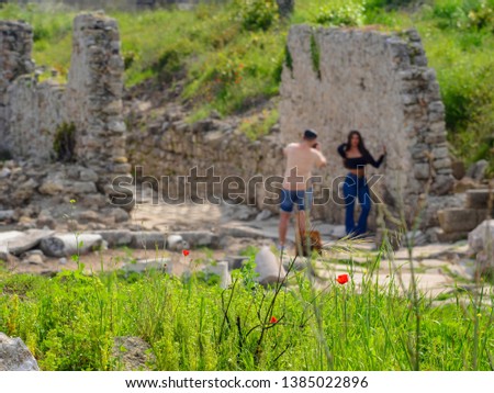 Side, Turkey - April 19 - 2019: Red poppies on a blurred background of tourists taking photos next to the ancient ruins