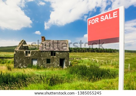 Derelict house in a rural situation with blank "For Sale" sign