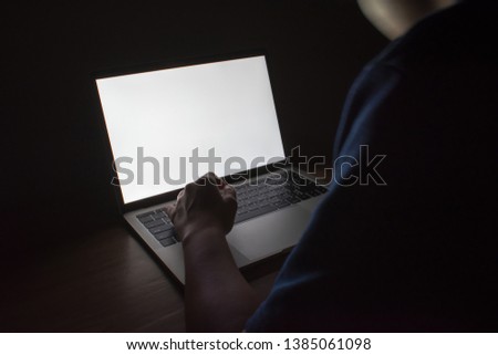 Picture of white light from a laptop on a wooden table in a dark room.