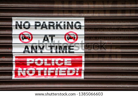 Sign on a shop shutter "No Parking at any time. Police Notified!"