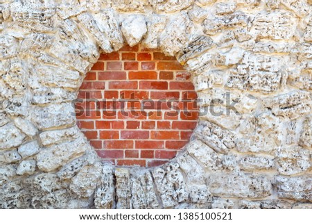 White stones randomly laid out form a round hole in which the red brick masonry is visible. Background image