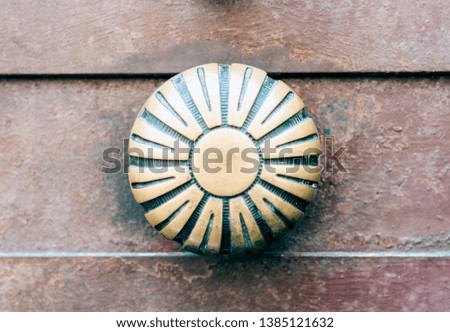 Exterior vintage door handle with a bronze finish on a brown front door in historic building Catania, Sicily, Southern Italy