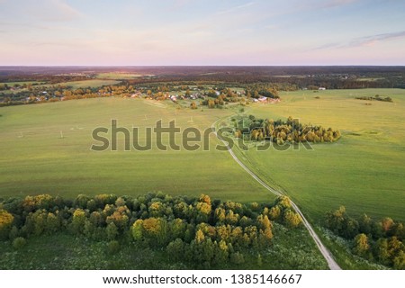 Top view of the agricultural fields and asphalt road stretching to the horizon against the evening sky. Aerial photography