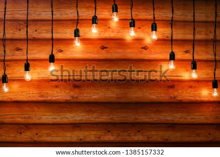 A modern dark loft style interior. Wooden planks with hanging light bulbs. Christmas and New Year background. Rustic wedding photo zone. Boho marriage decor. Design element. Copy space.