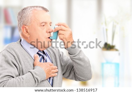 Mature man treating asthma with inhaler at home Royalty-Free Stock Photo #138516917