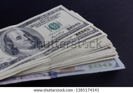One hundred dollar bills on a dark background.