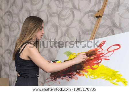 Young woman artist painting at home creative tools close-up. Girl in Painting Studio. Smiling girl paints on canvas with oil colors in workshop