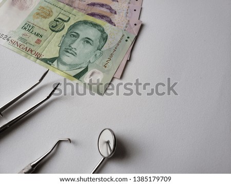dentist utensils for oral review and singaporean banknotes 