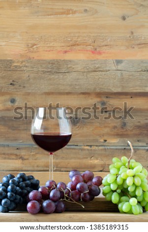 Glass of red wine with three kinds of grapes