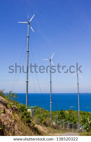 Stock Photo - Series of wind power generators in clear blue sky background.
