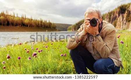 a man photographer takes a photo on the camera against a beautiful landscape. Lifestyle and travel concept. Toned