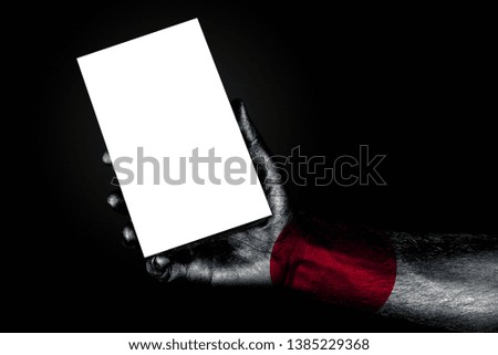 hand with painted flag Japan holding a large white sheet with space for an inscription, mock up. Horizontal frame
