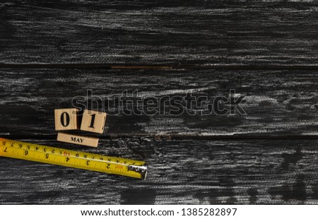 May 1 text wooden block calendar and tape measure on black wooden background for Worker day, Labor day, labour day.
