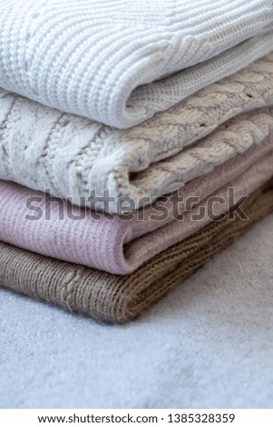 Soft fluffy textile plaids of different colors in one pile.  Winter sweaters are stacked on top of each other.