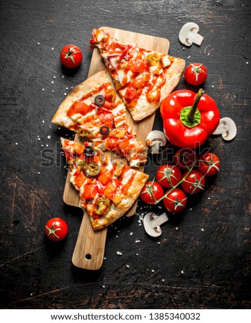 Slices of Mexican pizza with bell peppers and tomatoes. On dark rustic background