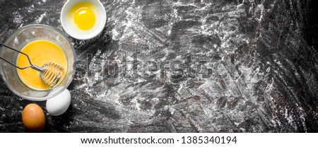 Eggs in bowls. On rustic background with flour