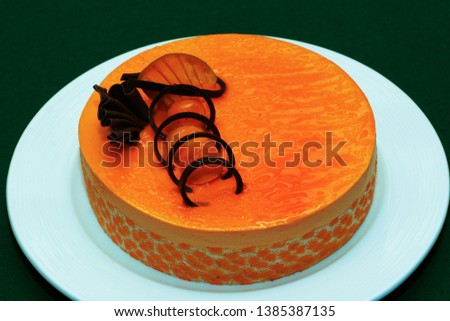 Decoretive Mango cake displayed in a white plate on green bacground