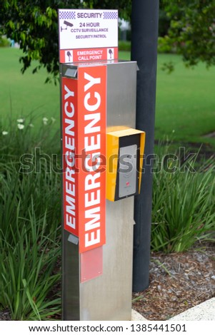 An emergency button telephone intercom system on the side of a public path.