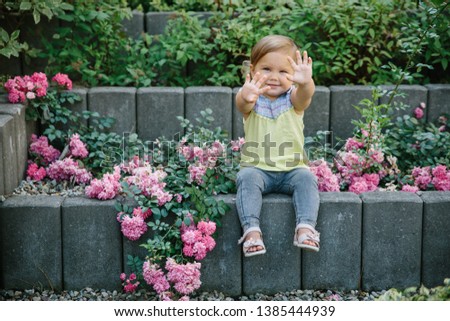 Baby girl outside playground laughing in flowers