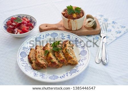 Close up Picture on the traditional baked czech spring dish, kind of salt cake or quiche, made from eggs, smoked ham, bread, pork meat and parsley, served on rustic plate with fresh tomato salad.  