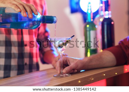 Barman pouring martini into glass at pub, closeup