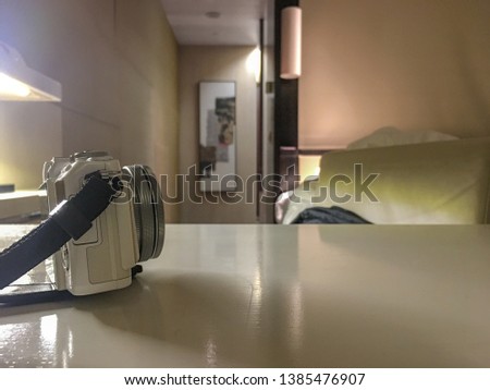 Side view of white mirror less camera on table with blurred room background with copy space