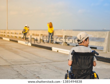 A child on wheelchair on the bridge background and daylight, Amateur photographer, He has a camera hanging neck, Life in the education age of disabled children, Happy disabled kid concept.