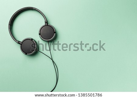 Black headphones on mint background. Headphones on a pastel background. Flat lay top view copy space. Minimal style with colorful paper backdrop. Music concept