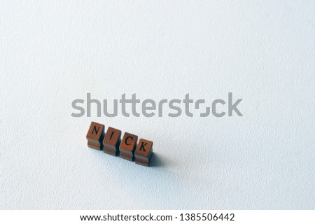 NICK - popular boys name formed of wooden blocks on a white background. Nick common male name.