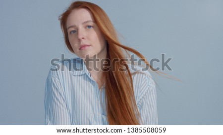 Ginger head red hair, ginger hair model with blue big eyes in studio with blowing hair. Beauty straight shiny hair blowing,