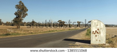 lone rural rustic rusty farm covered school bus station stop on a long empty sealed road in a cattle farming district, rural New South Wales, Australia